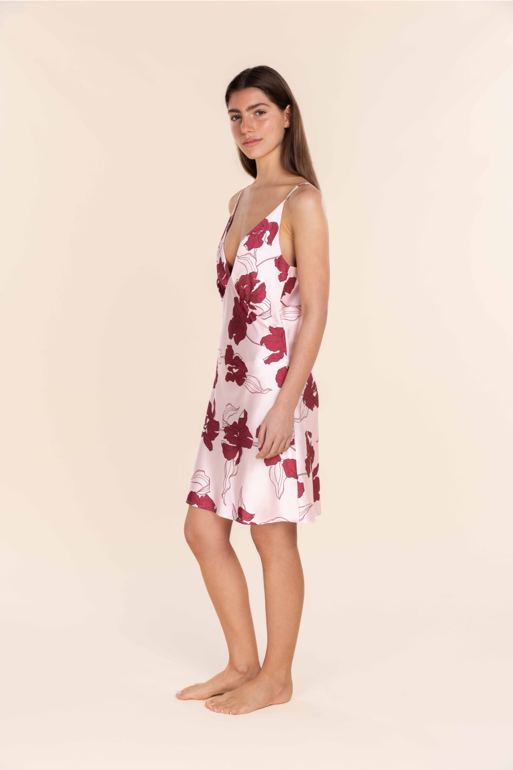 Woman wearing a floral slip dress on a beige background