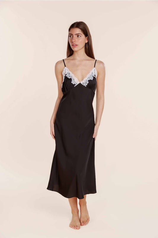 Woman wearing a black slip dress with lace trim on a beige background