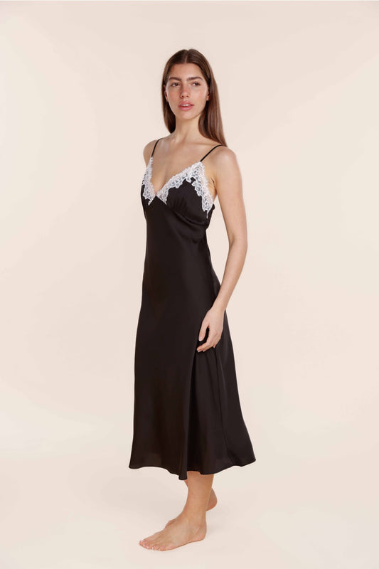 Woman wearing a black slip dress with lace trim on a beige background