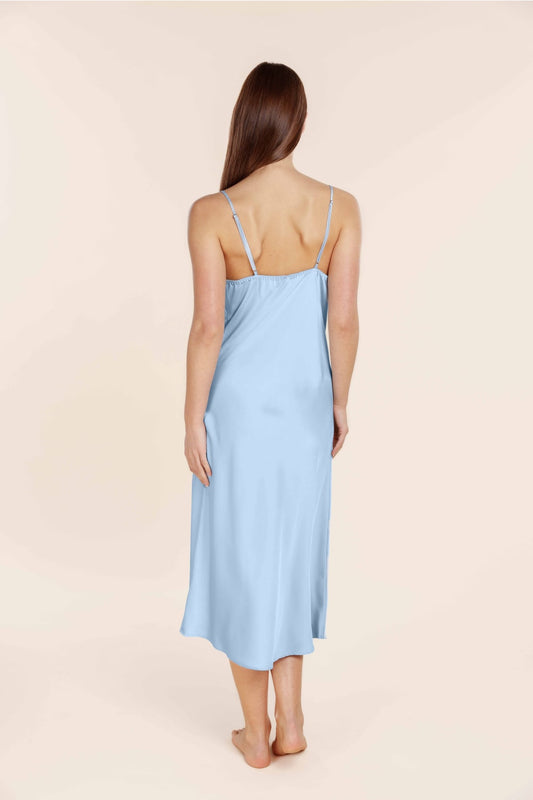 Woman wearing a light blue slip dress against a beige background