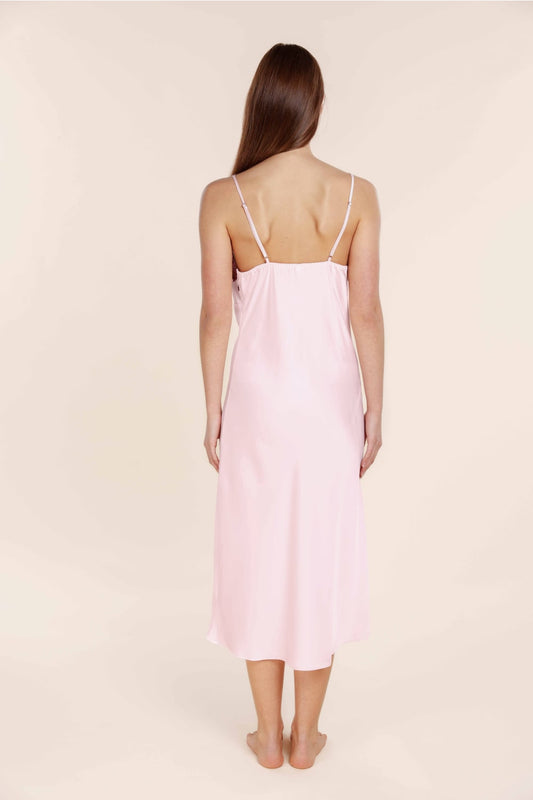 Woman wearing a light pink slip dress against a beige background