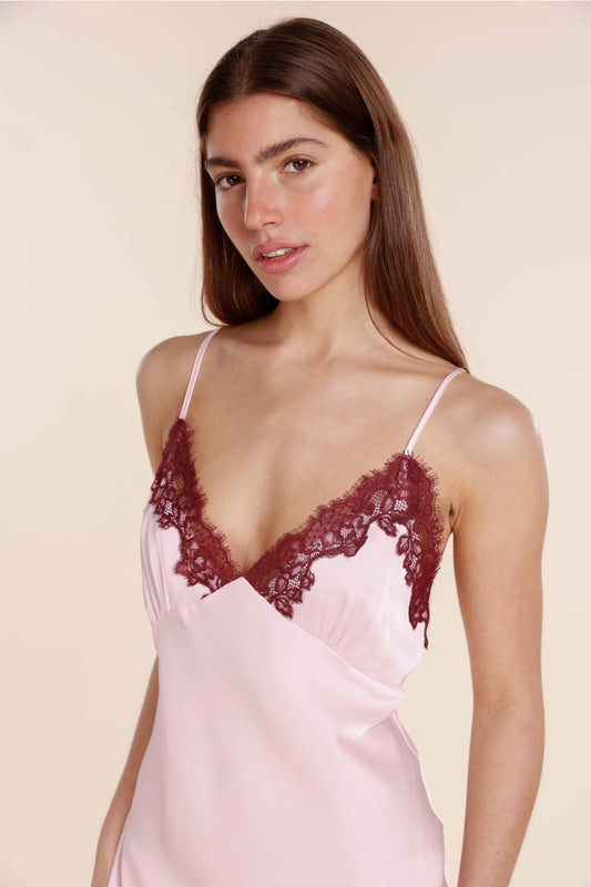Woman wearing a pink satin nightgown with lace details on a beige background