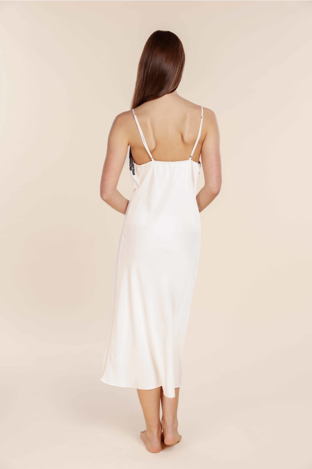 Woman wearing a white slip dress against a beige background