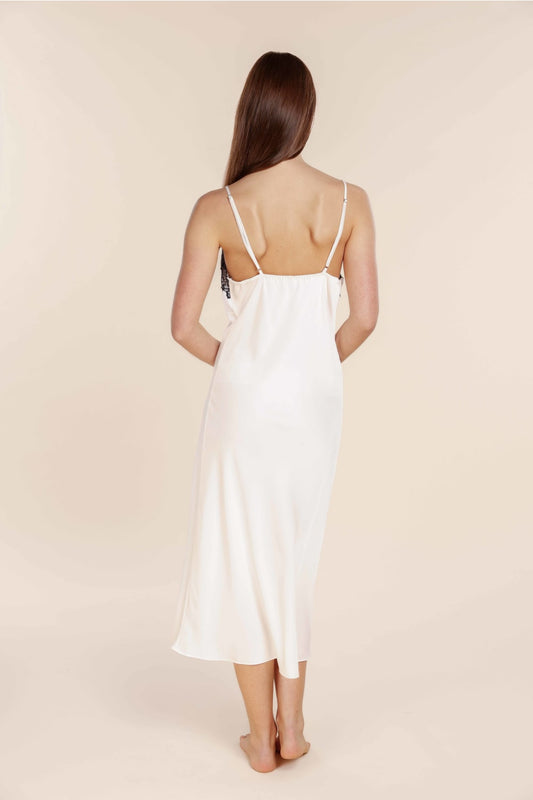 Woman wearing a white slip dress against a beige background