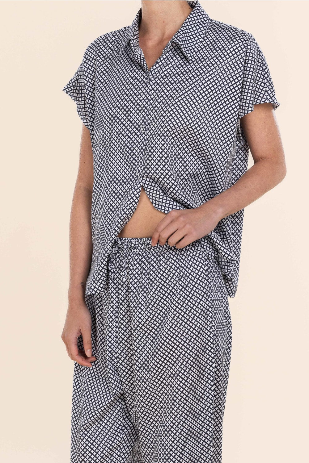 Person wearing a black and white patterned outfit on a beige background