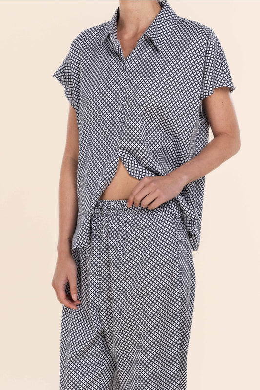 Person wearing a black and white patterned outfit on a beige background