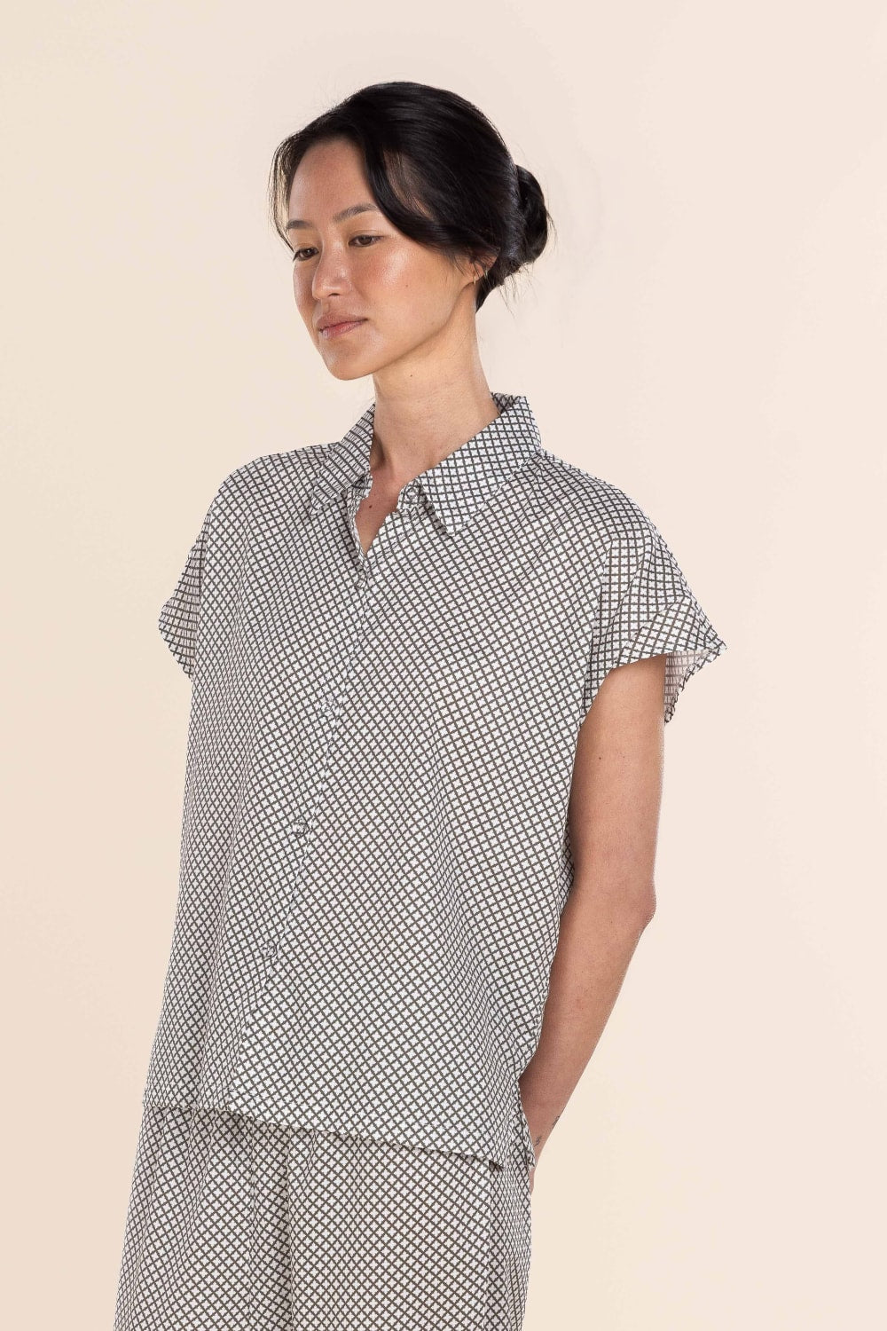 Woman wearing a black and white checkered outfit on a beige background