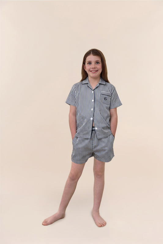 Child wearing a striped shirt and shorts set on a beige background