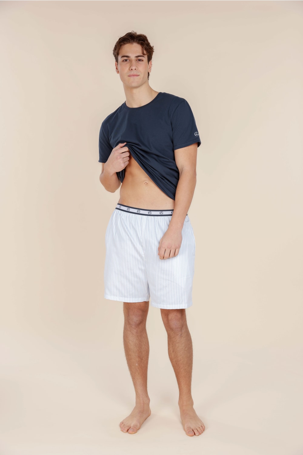 Man wearing a navy t-shirt and white shorts on a beige background