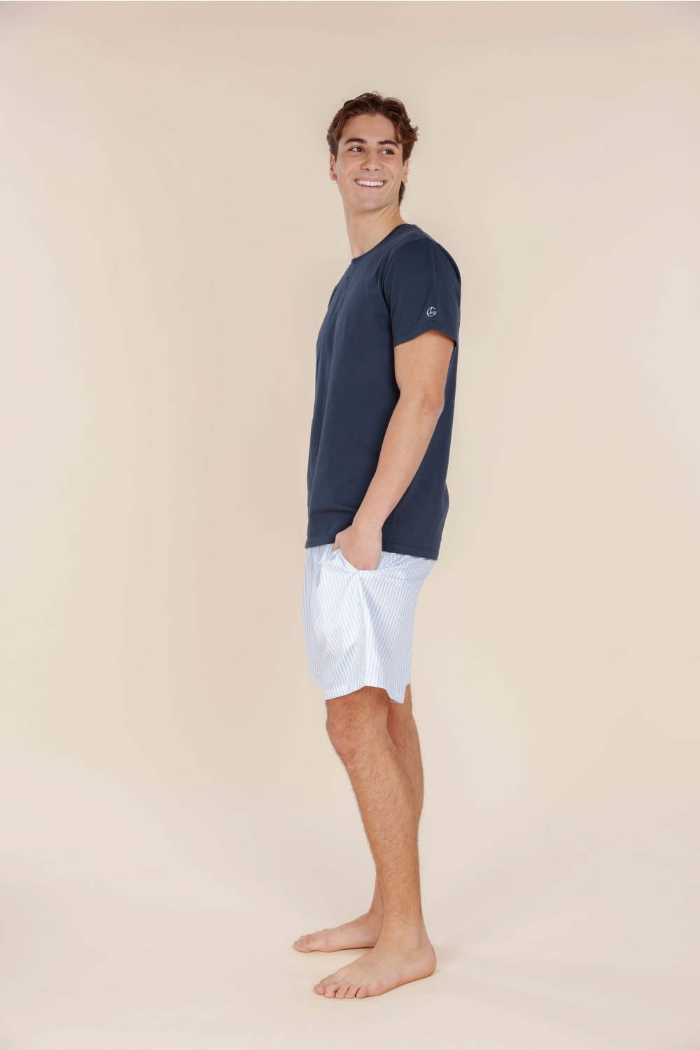 Man wearing a navy t-shirt and white shorts on a beige background