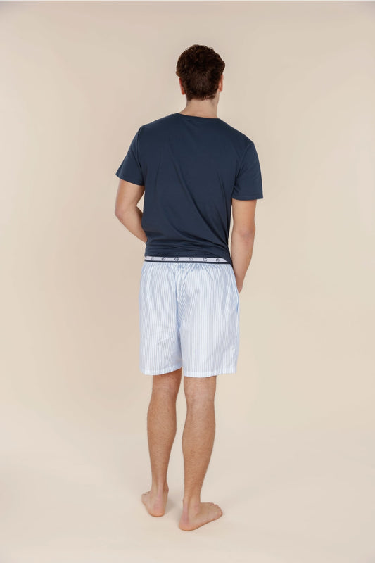 Man wearing navy t-shirt and light blue shorts on a beige background