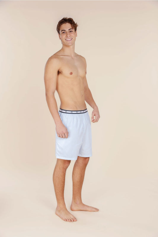 Man wearing white boxer briefs with a dark waistband on a beige background