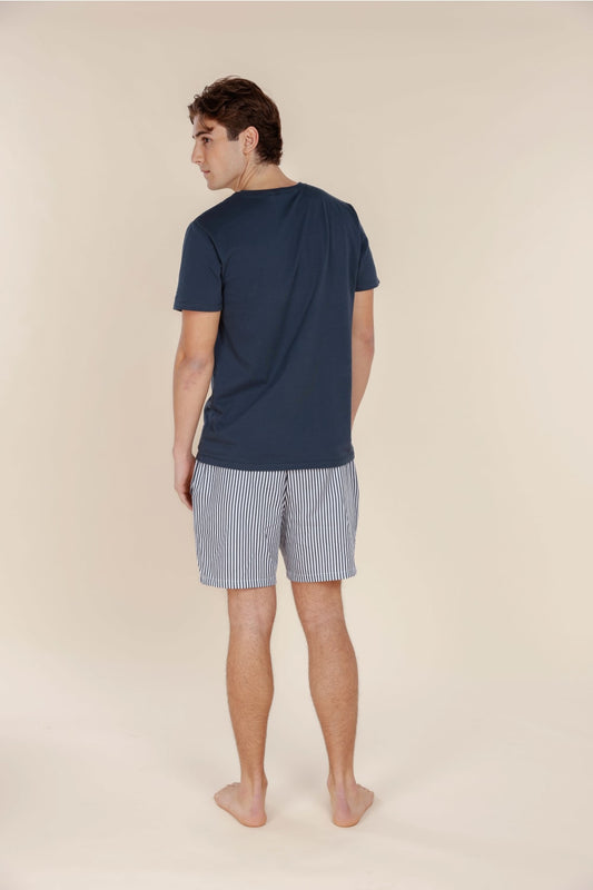 Man wearing a navy t-shirt and striped shorts on a beige background