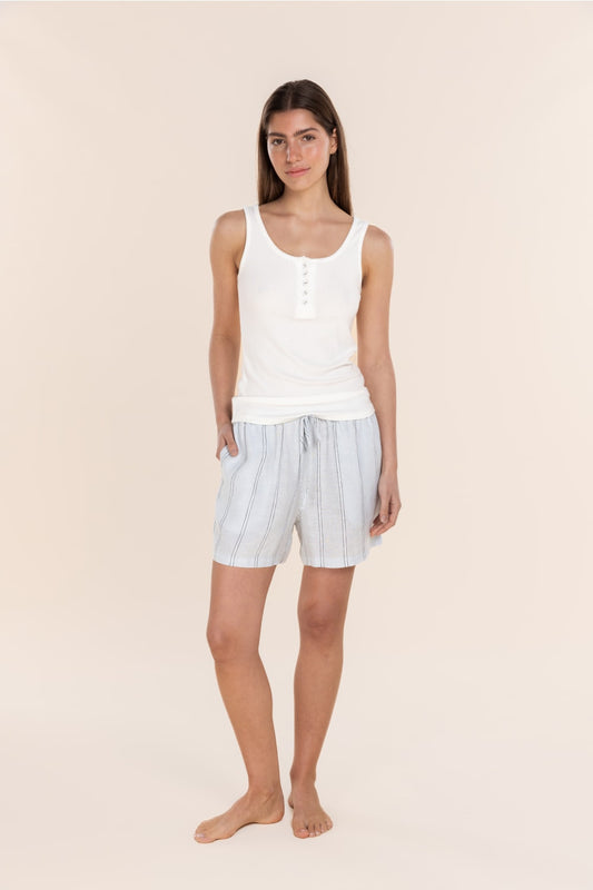 Woman wearing a white tank top and striped shorts on a beige background