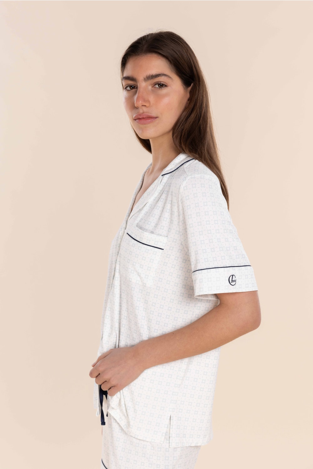 Woman wearing a white outfit with black trim on a beige background