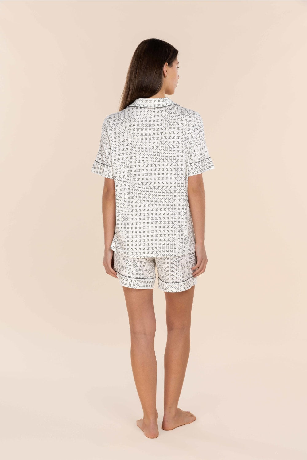 Woman wearing a patterned pajama set on a beige background