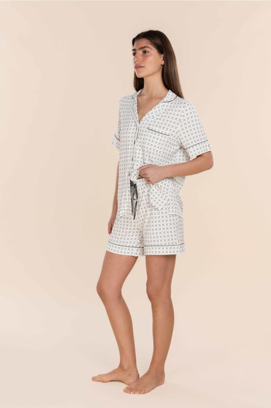 Woman wearing a white patterned pajama set on a beige background