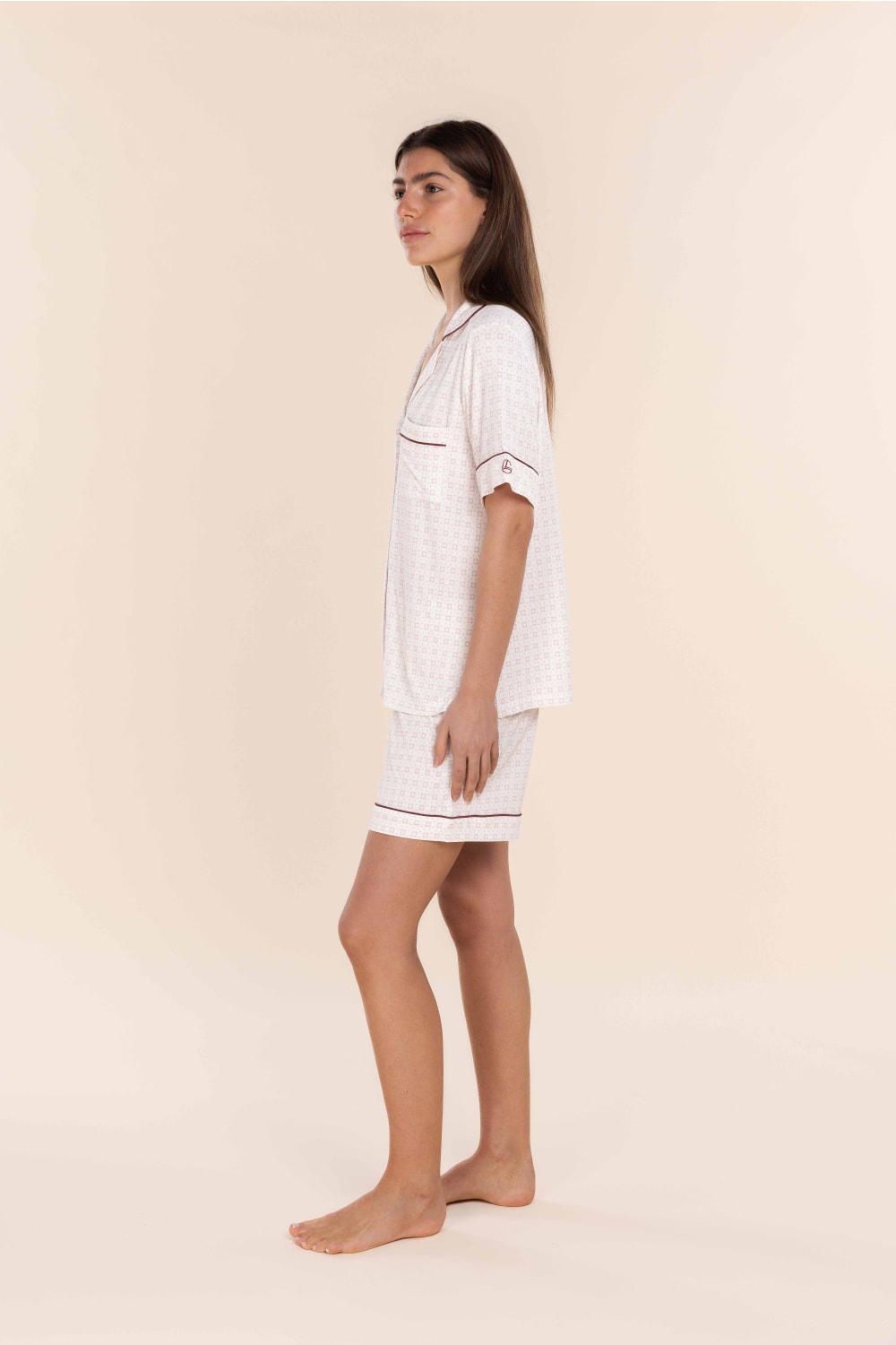 Woman wearing a white outfit with a pattern on a beige background