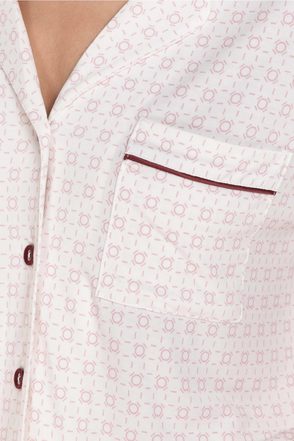Close-up of a white shirt with a subtle pattern and brown buttons and trim.