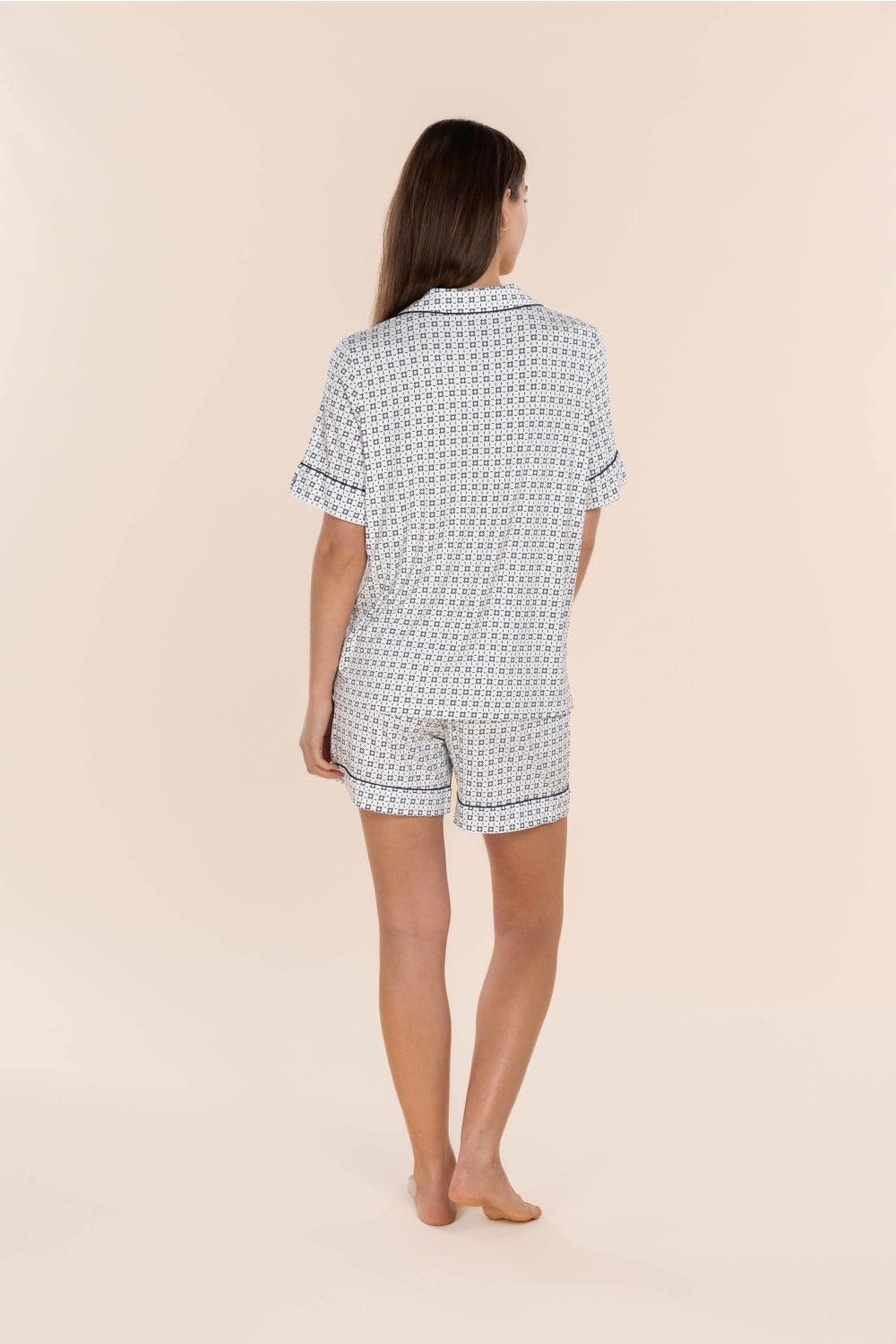 Woman wearing a black and white patterned pajama set on a beige background