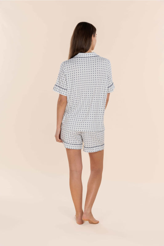 Woman wearing a black and white patterned pajama set on a beige background