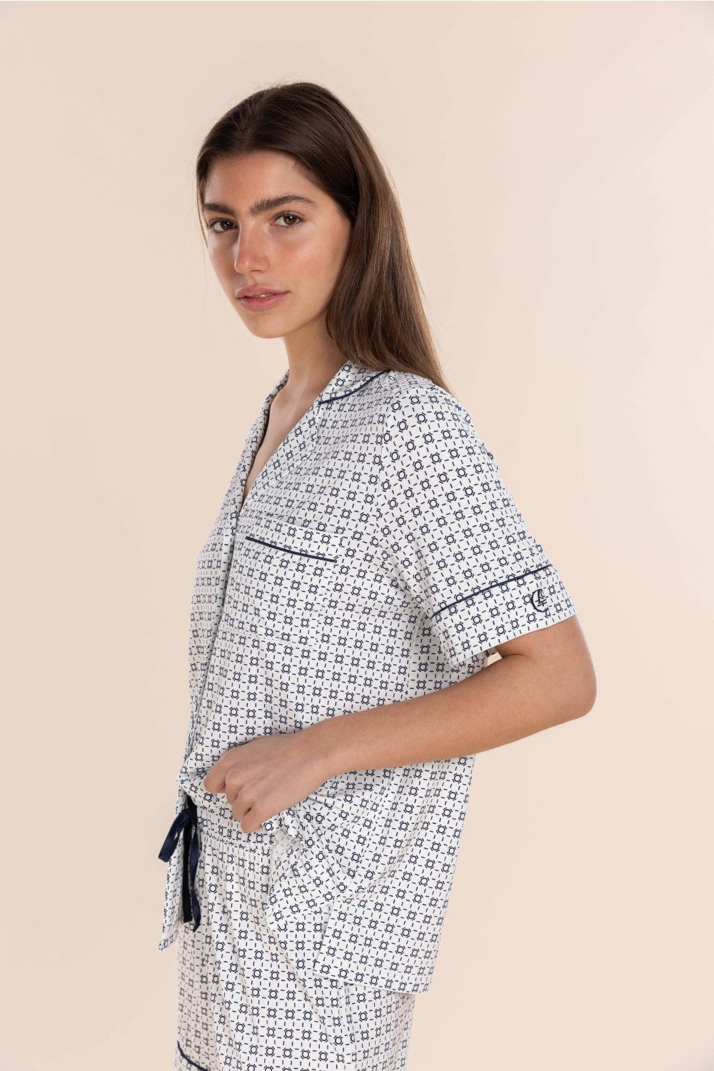 Woman wearing a patterned shirt and pants set on a beige background