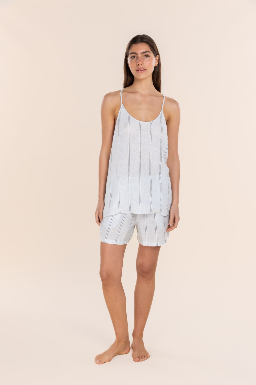 Woman wearing a light blue striped pajama set on a beige background