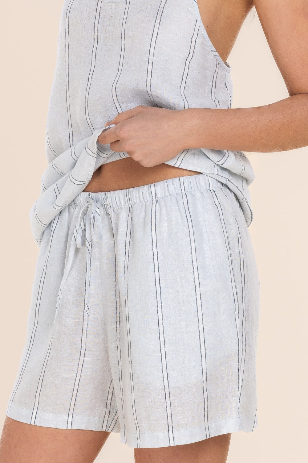 Light blue striped shorts worn by a person on a beige background