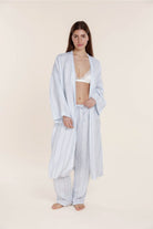 Woman wearing a light blue striped robe on a beige background