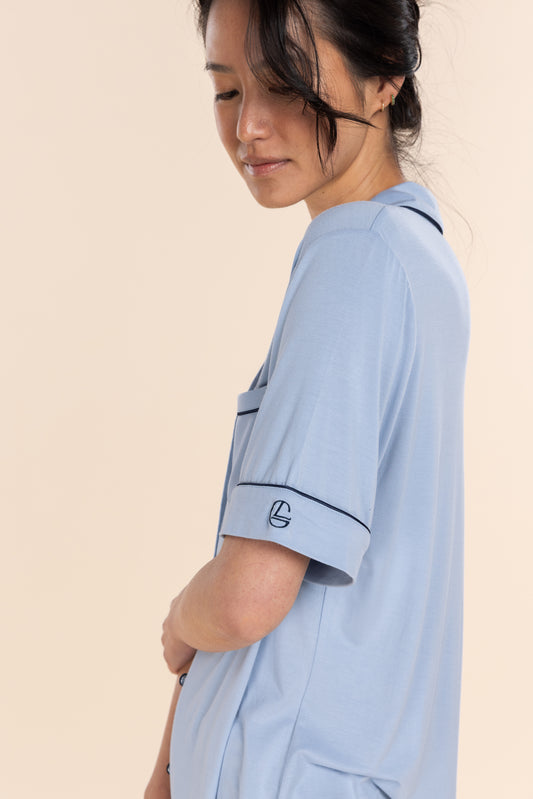 Woman wearing a light blue shirt with a logo on a beige background