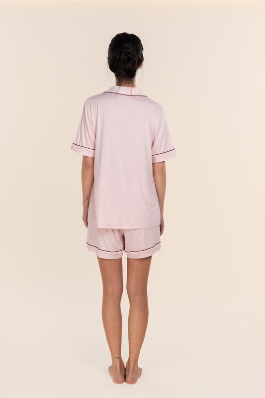 Person wearing a light pink pajama set with a plain background