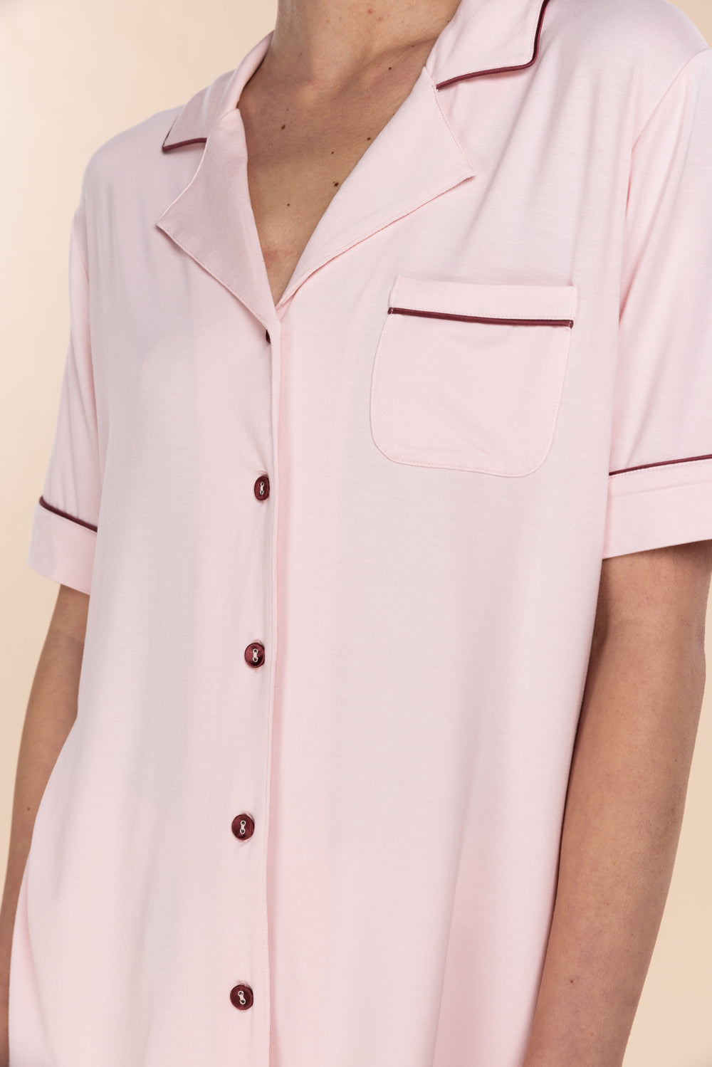 Pink pajama top with buttons on a neutral background