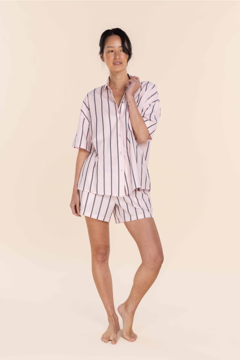 Woman wearing a striped pajama set on a beige background
