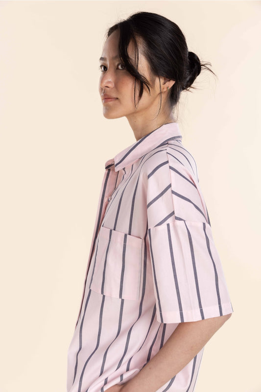 Woman wearing a light pink shirt with dark vertical stripes on a beige background