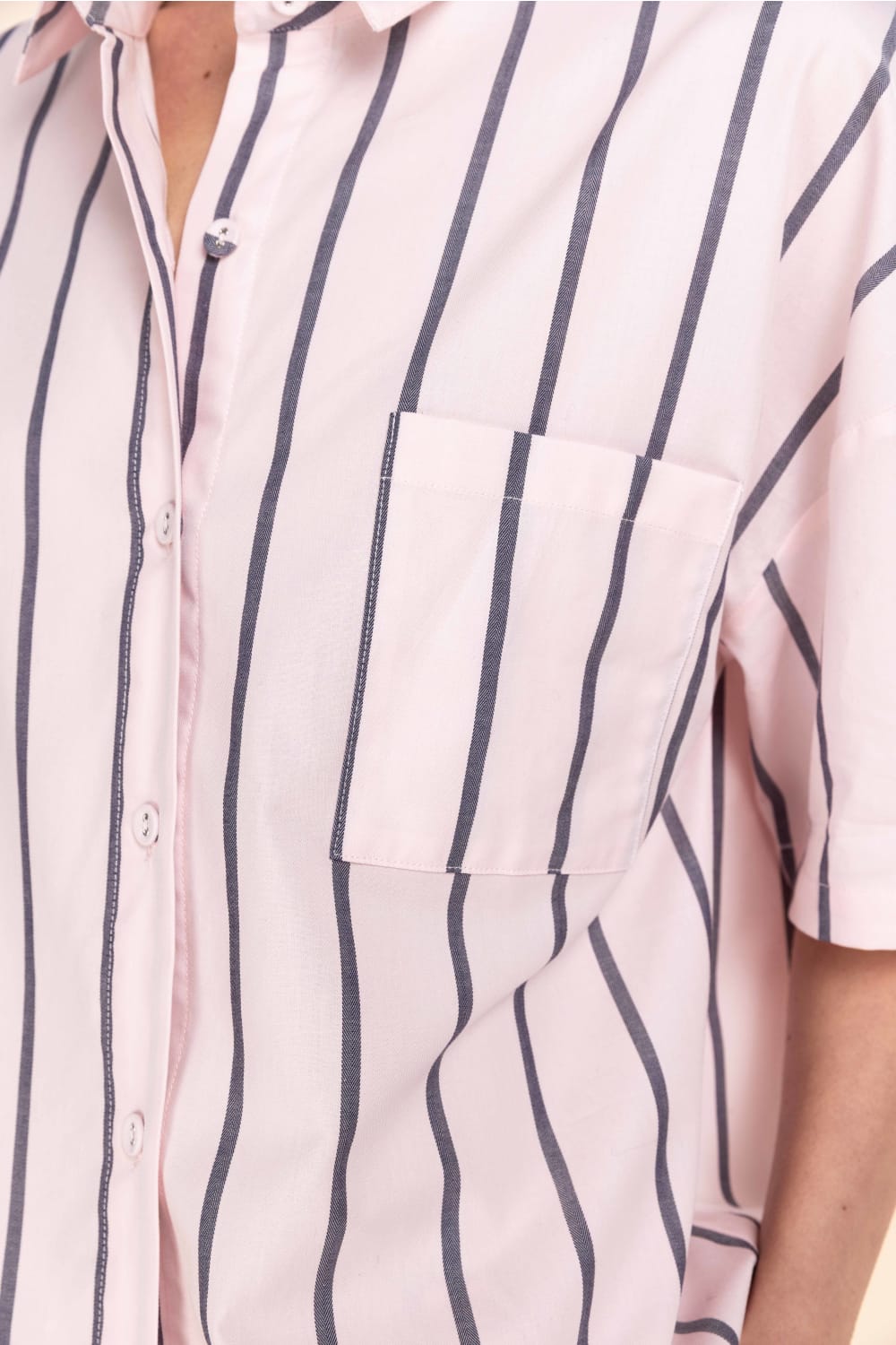 Close-up of a pink shirt with blue vertical stripes on a white background