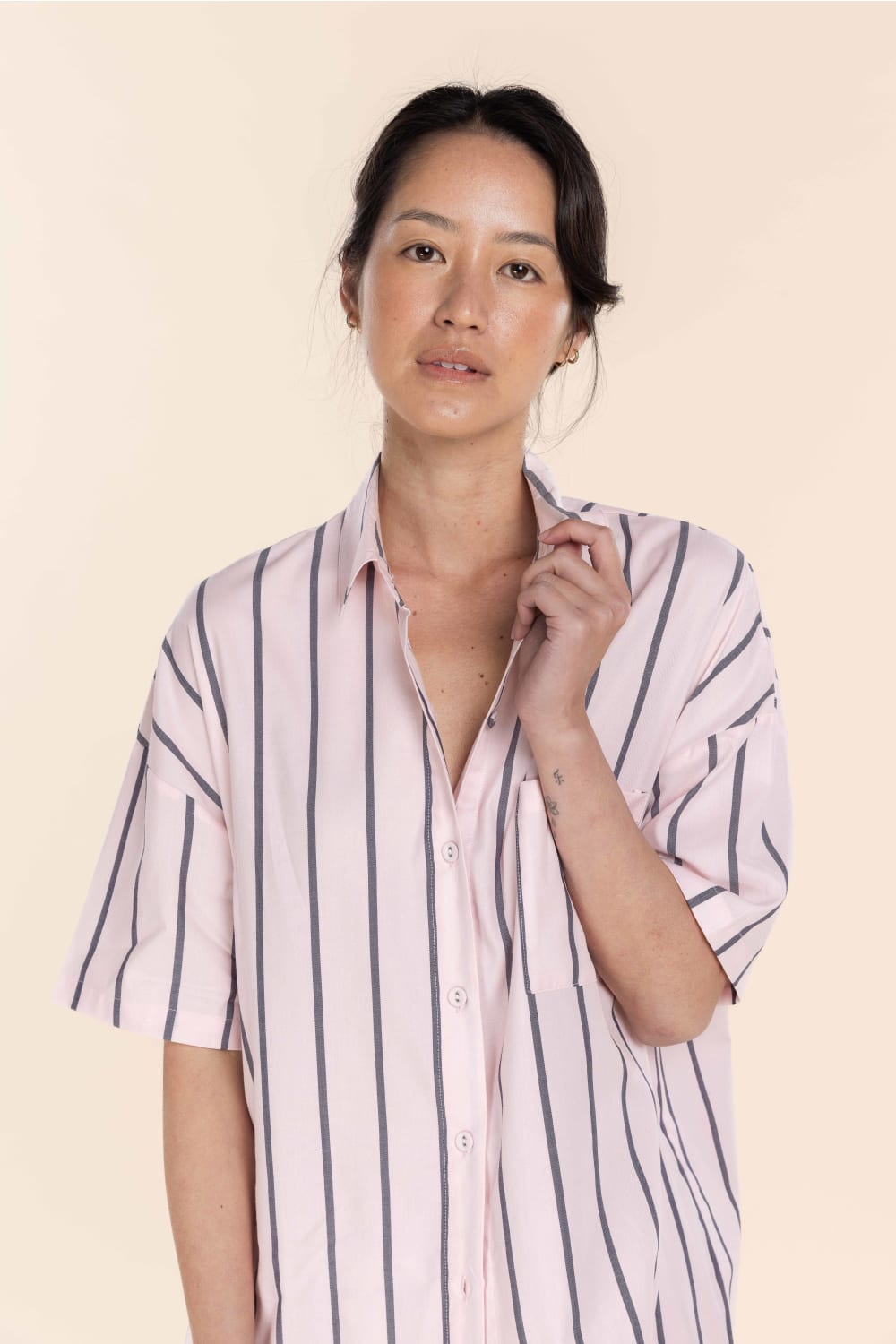 Woman wearing a light pink and white striped shirt against a beige background