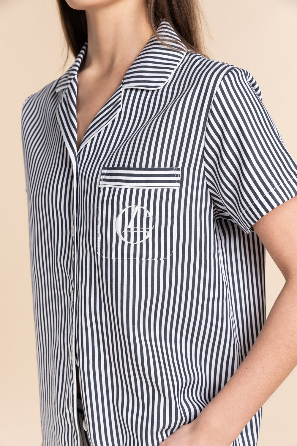 Navy and white striped shirt with a logo on a beige background