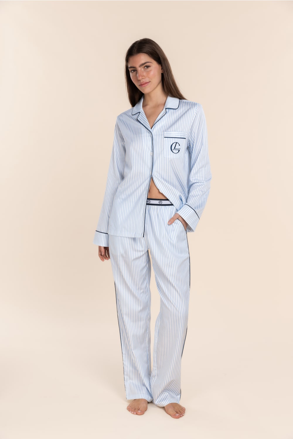 Woman wearing a light blue striped pajama set on a beige background