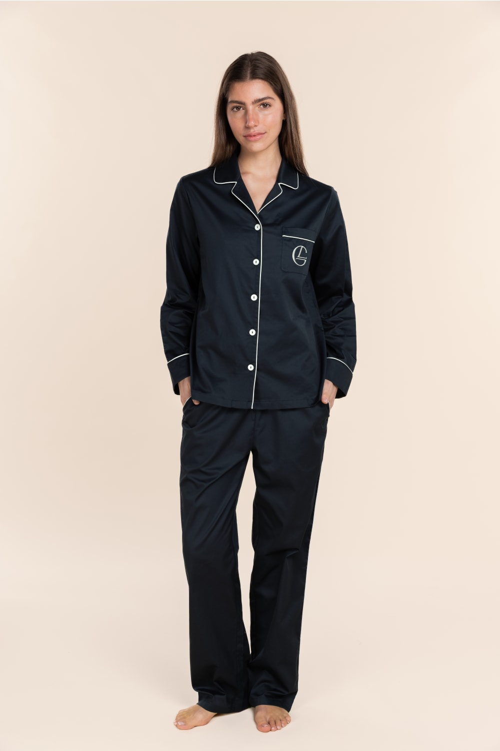 Woman wearing black pajamas with white piping on a beige background