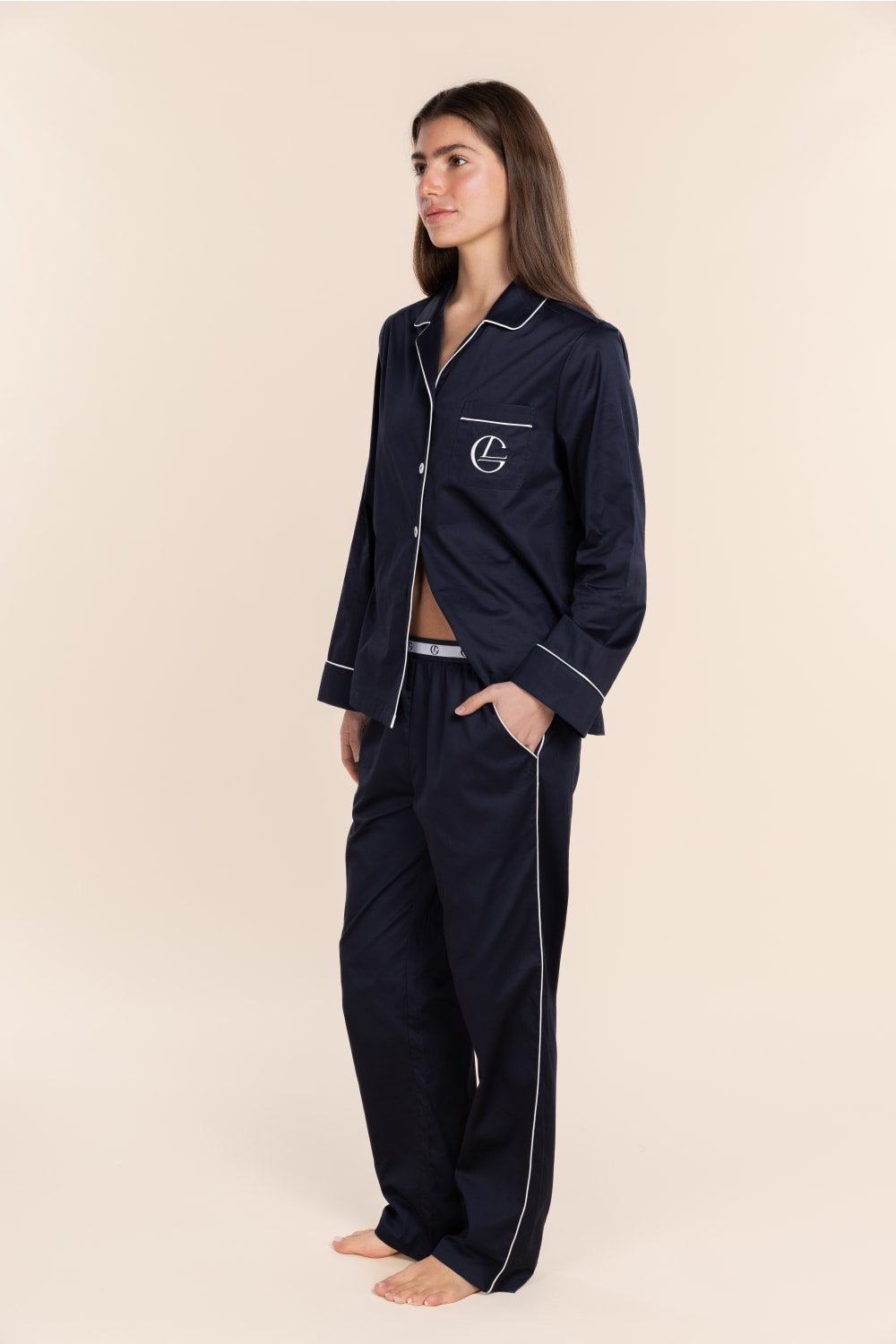 Woman wearing navy pajamas with a logo on a beige background