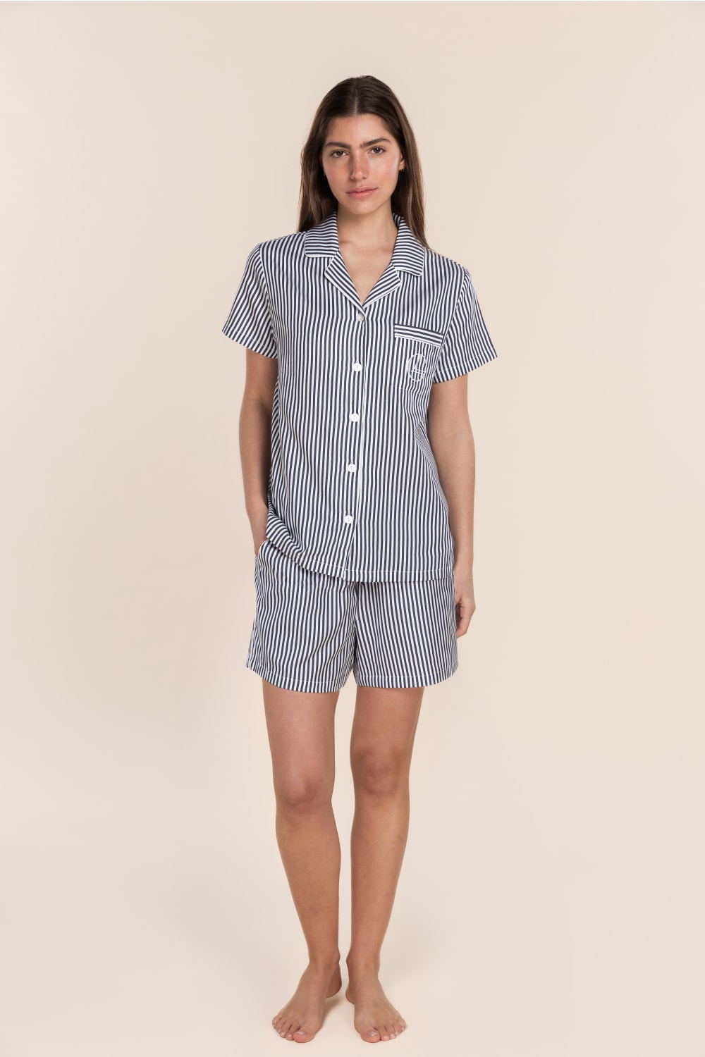 Woman wearing a navy and white striped pyjama set on a beige background