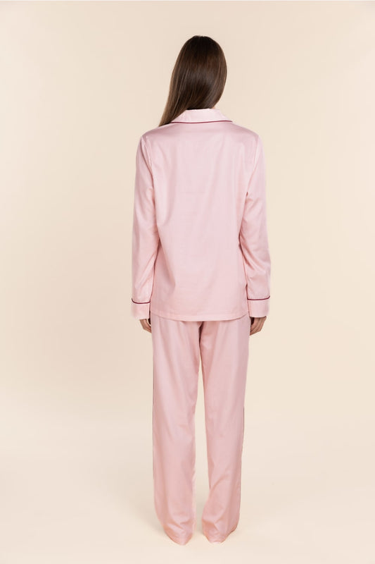 Person wearing a pink pajama set on a beige background