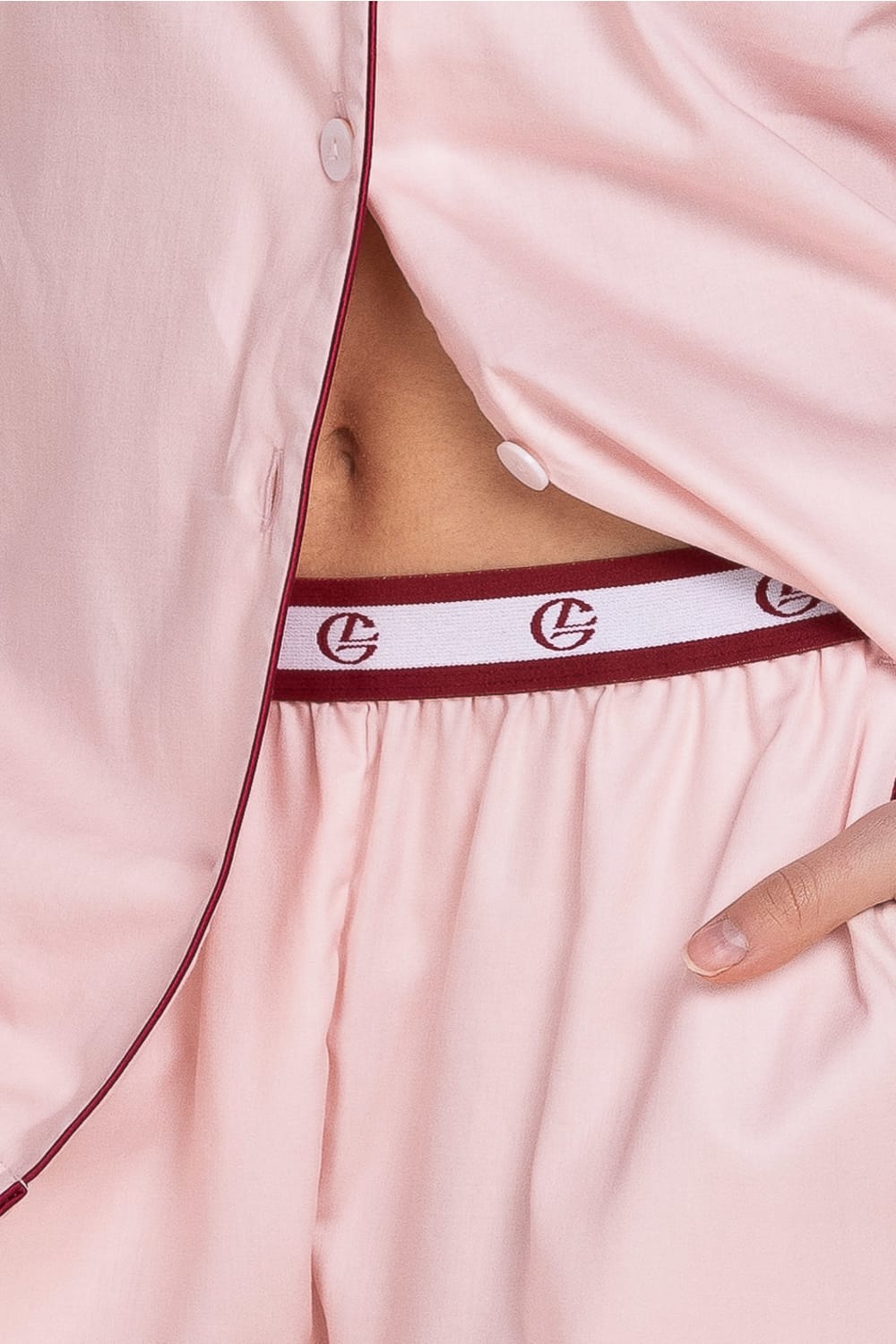 Close-up of a pink satin nightgown with a red waistband featuring a logo.