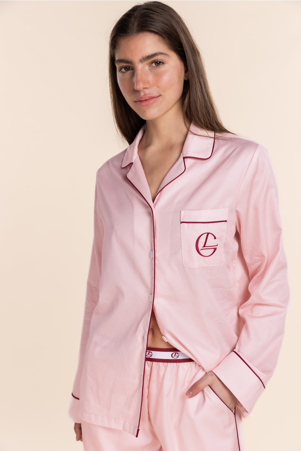Woman wearing pink pajamas with a logo on a beige background