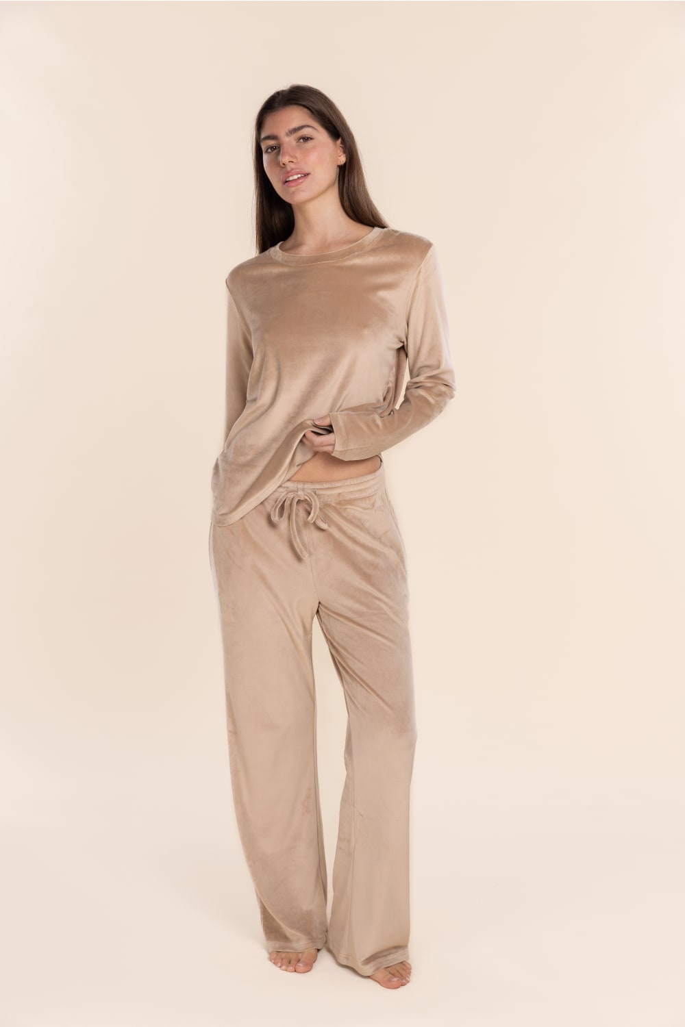 Woman wearing a beige long-sleeve top and pants on a beige background