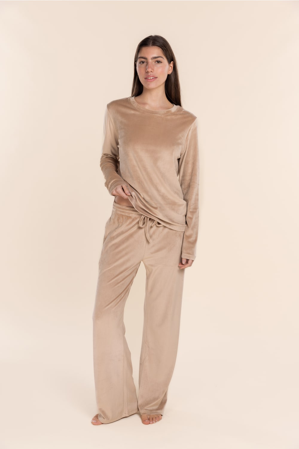 Woman wearing a beige long-sleeve top and pants on a beige background