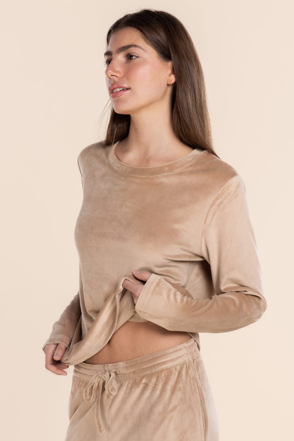 Woman wearing a beige long-sleeve top and pants on a beige background