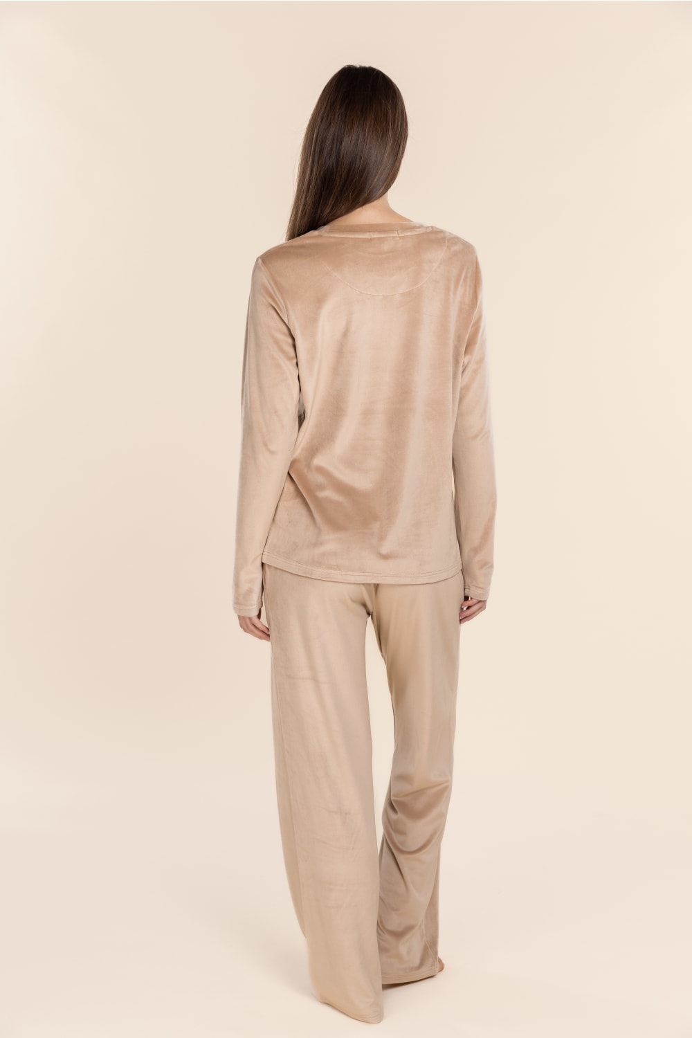 Woman wearing a beige outfit on a plain background