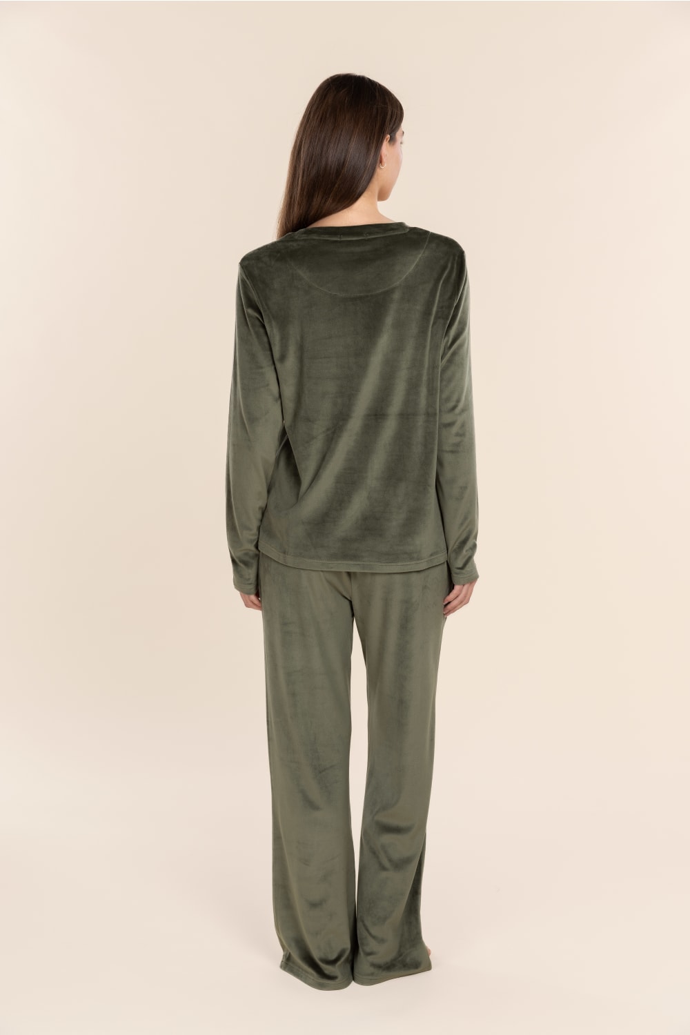 Person wearing a green velour outfit on a beige background