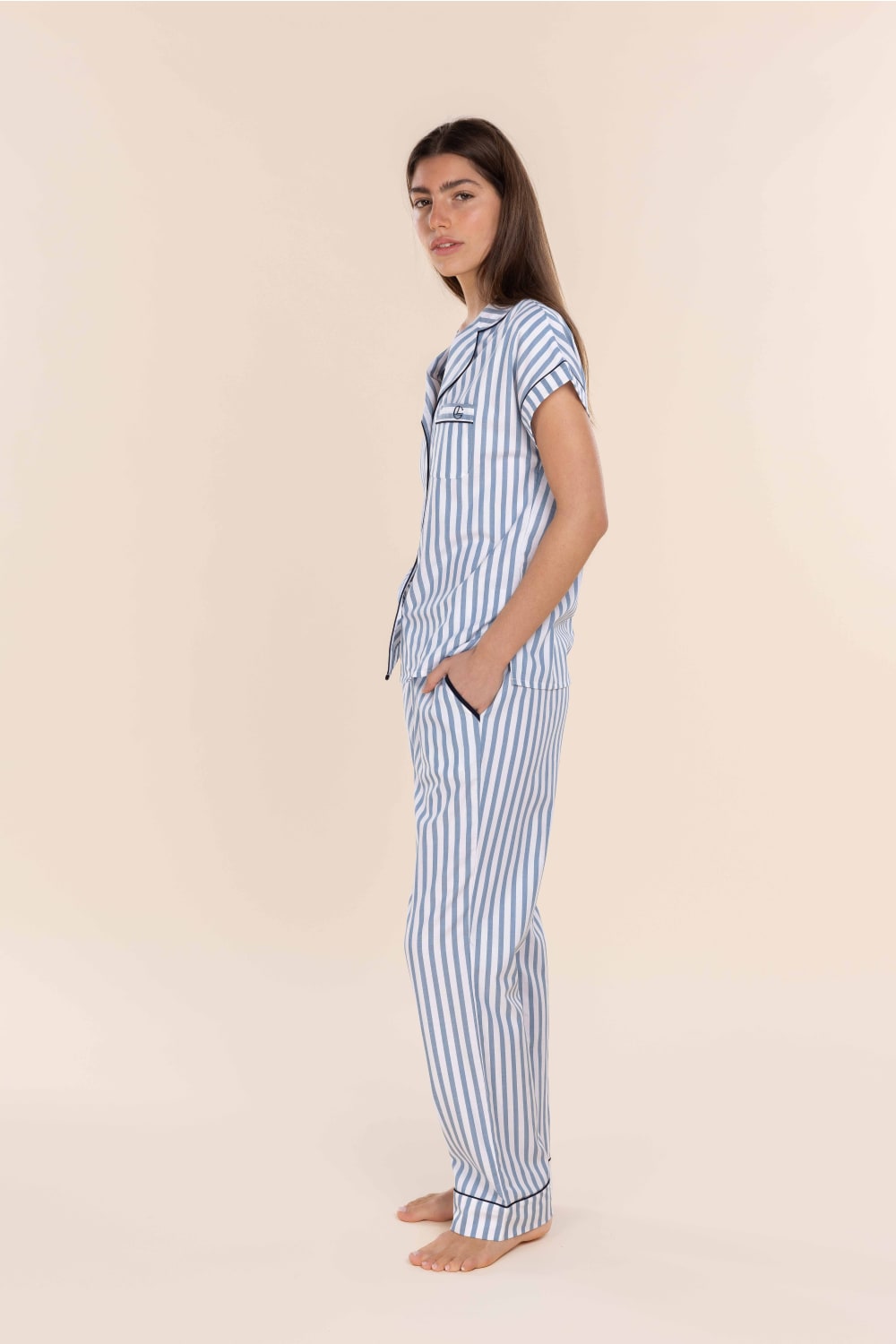 Woman wearing a blue and white striped pajama set on a beige background